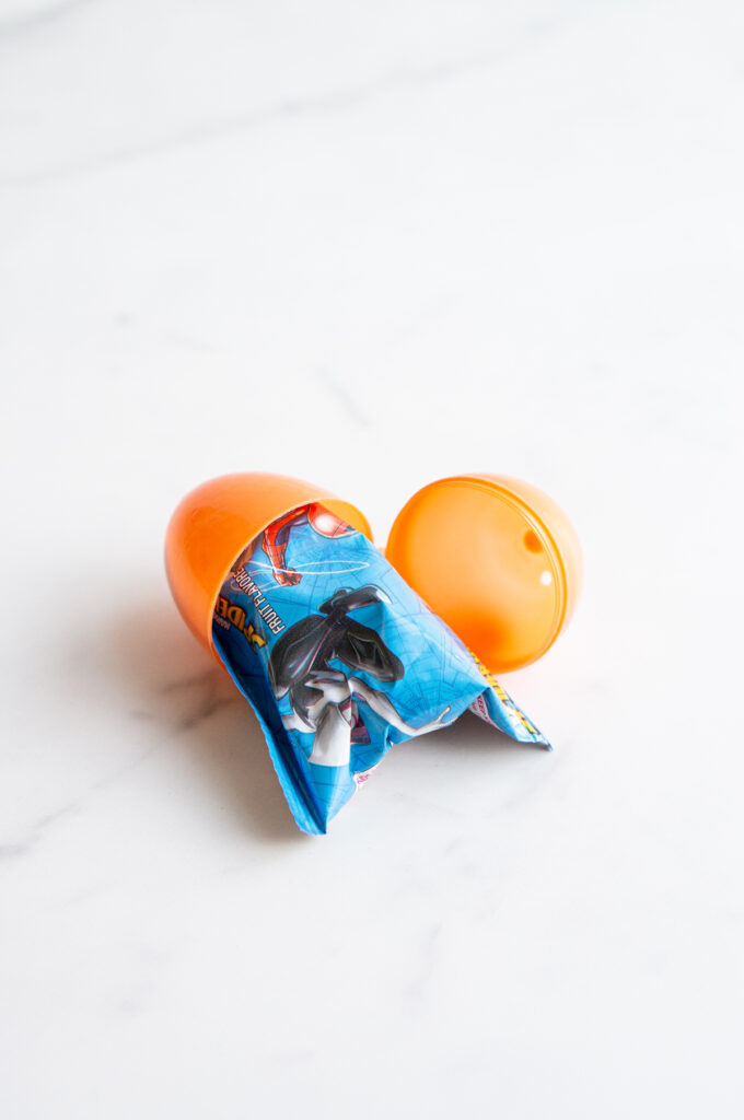 This image shows a plastic easter egg filled with non candy item of fruit snacks.