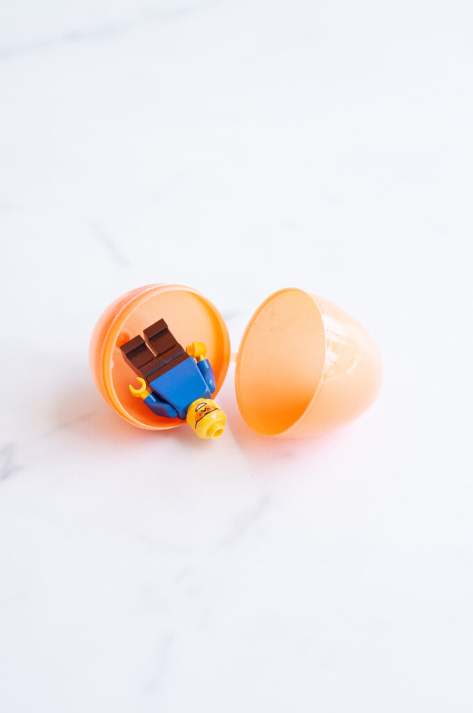 This image shows a plastic easter egg filled with non candy item of Lego men.