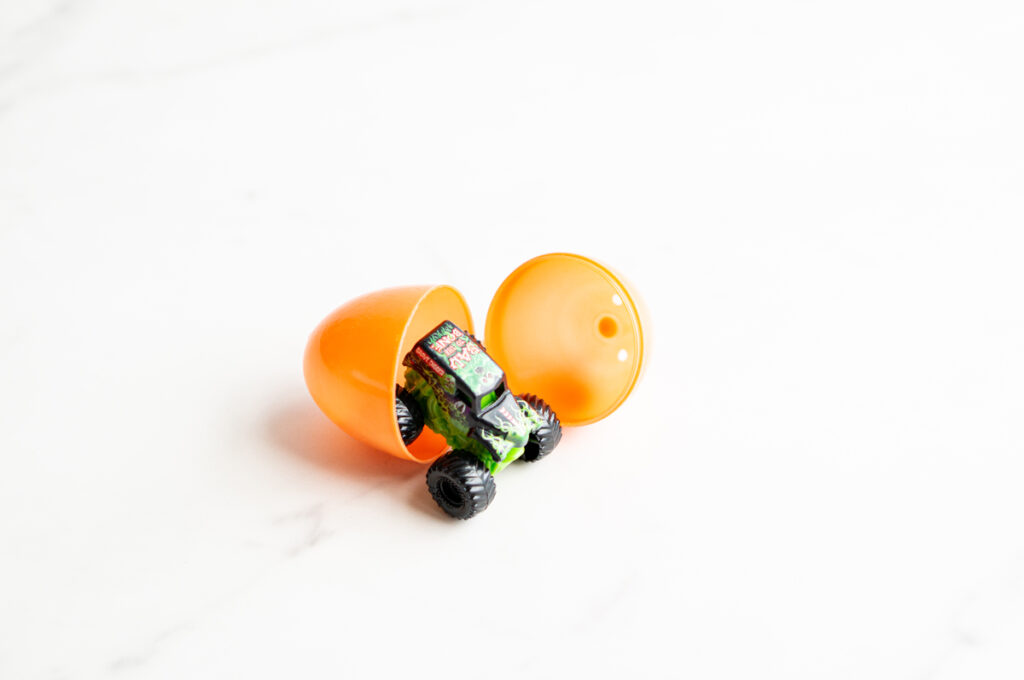 This image shows a plastic easter egg filled with non candy item of a mini monster truck.