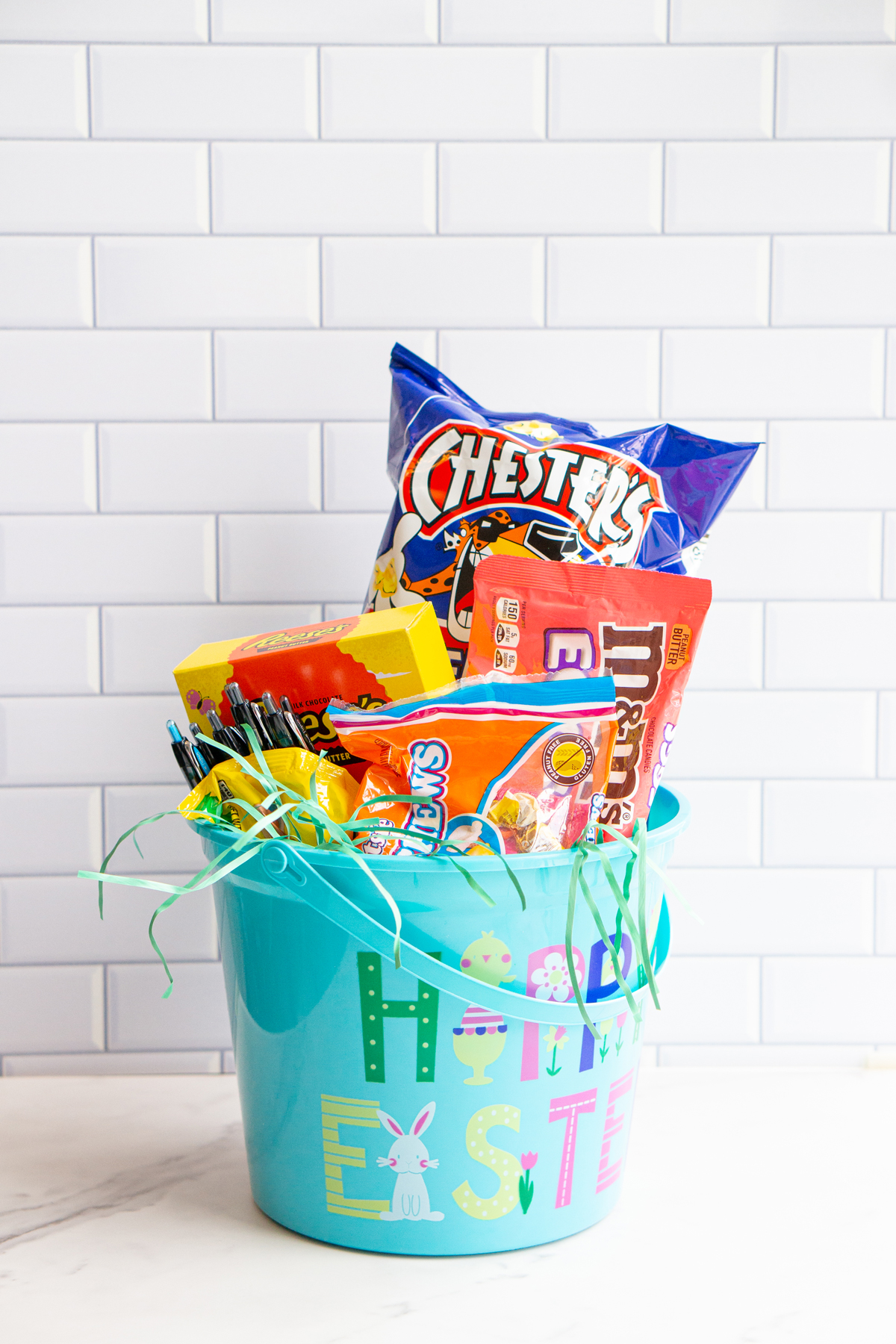 This image is of an adult Easter basket filled with snacks, candy, and pens.