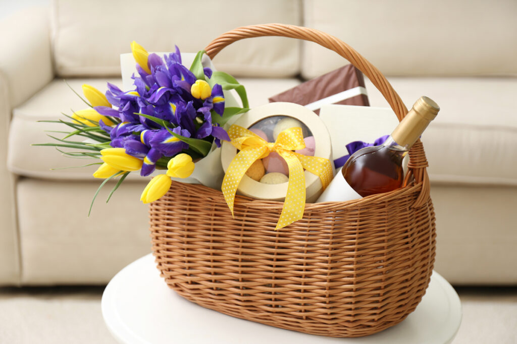 This is an image of an Easter basket filled with flowers, wine, and some Easter chocolate candy. 