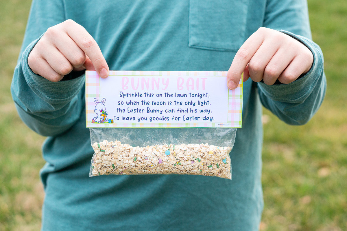 This image shows a boy holding up one of finished free bunny bait printable tags on top of a bag.