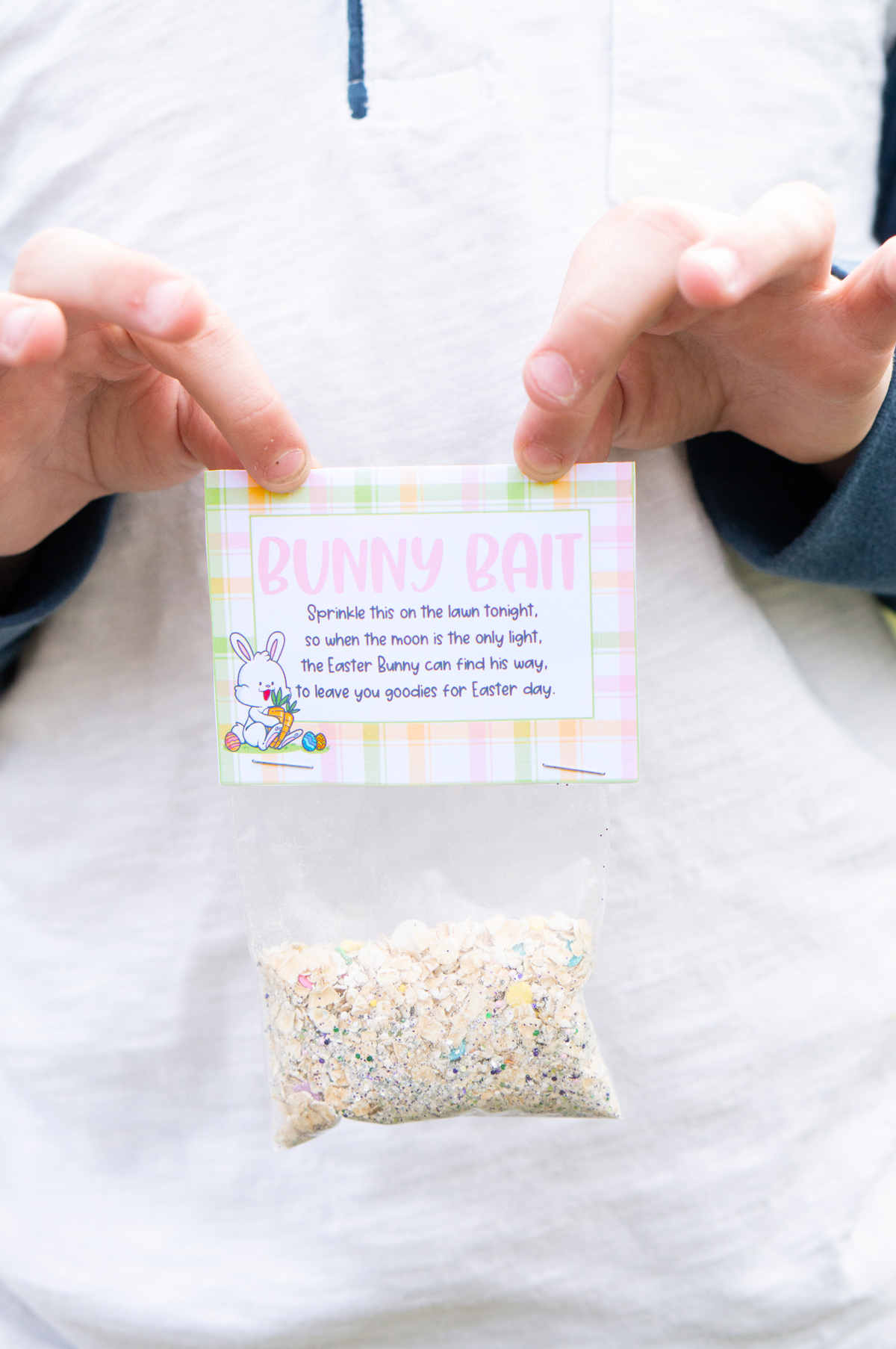 This image shows a boy holding up one of finished free bunny bait printable tags on top of a bag.