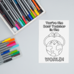 This image shows 1 of the free printable teacher appreciation cards you can color that you can download at the end of this post. The card is on a table surrounded by markers. The card says you're the best teacher in the world! and has a world that has a smiley face with two arms stretched above it's head making a heart with it's hands.