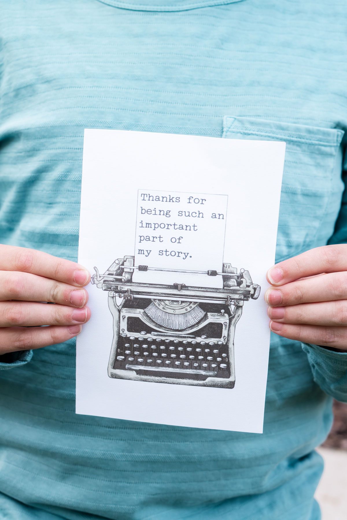 This image is of a child holding one of the free printable thank you cards for teacher appreciation or the end of the year. It says thank you for being an important part of my story and has a type writer.