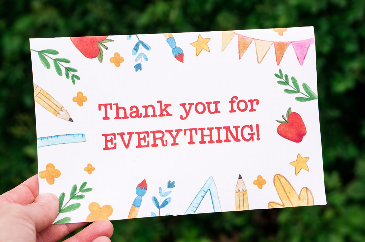 This image is of someone holding one of the free printable thank you cards for teacher appreciation or the end of the year. It says thank you for everything! and is surrounded by a border of school supplies.