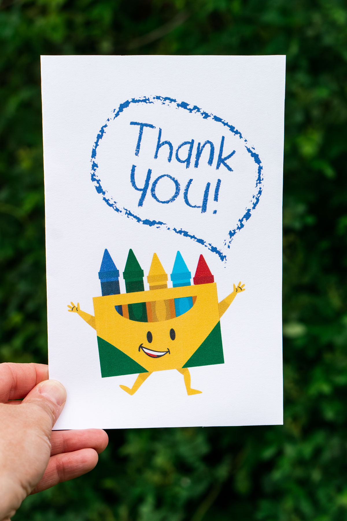 This image is of someone holding one of the free printable thank you cards for teacher appreciation or the end of the year. It has a pack of crayons that is saying thank you!