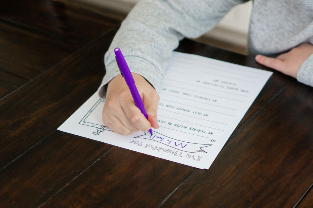 This image is of a child filling out the free printable teacher appreciation questionnaire you can download at the end of this post.