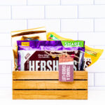 This image shows a wooden crate filled with various types of chocolate and a chocolate themed gift tag that says, Thanks choco-lot.