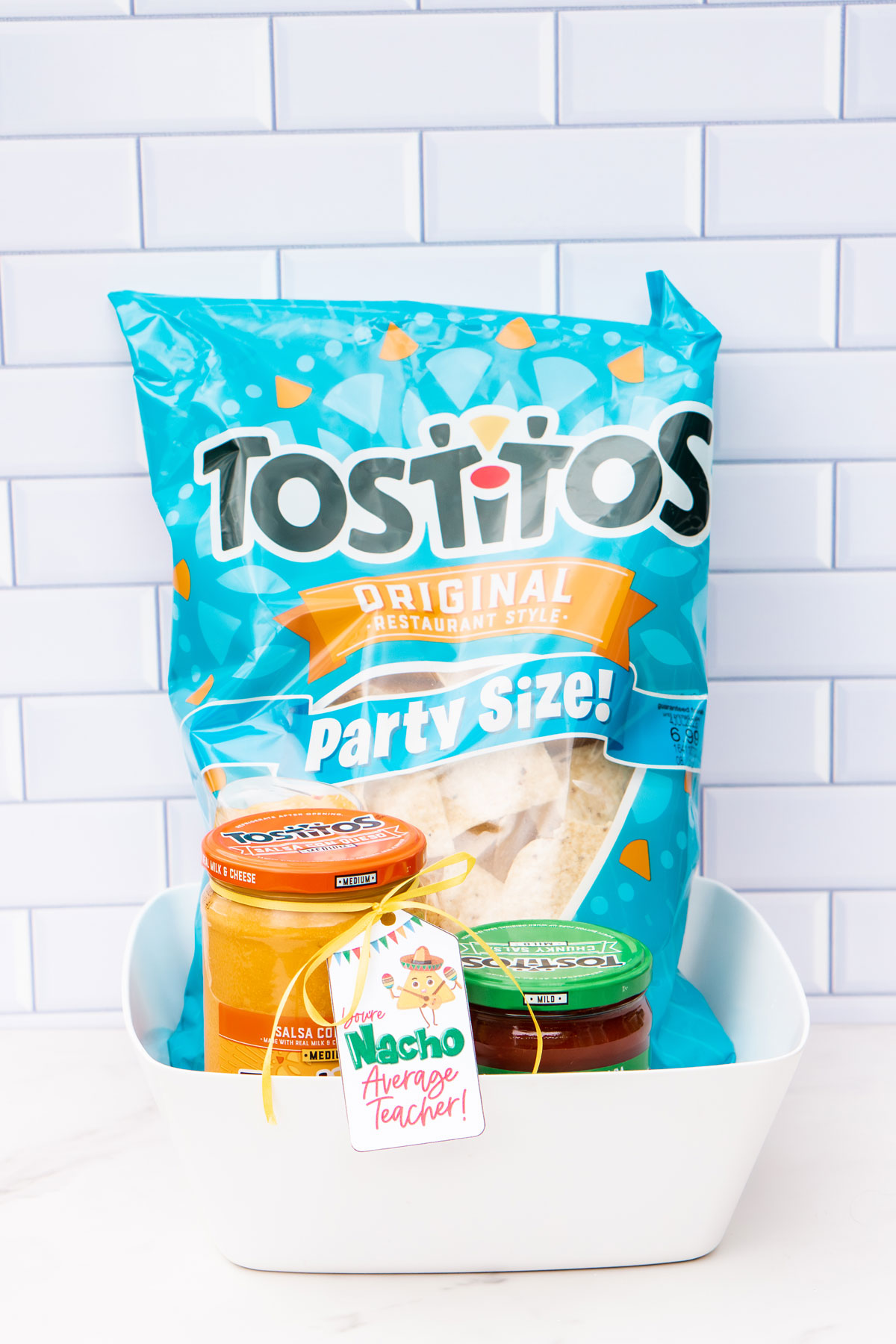This image shows a bag of Tostitos chips, queso cheese, and a jar of salsa. There is a tag that says You're nacho average teacher.