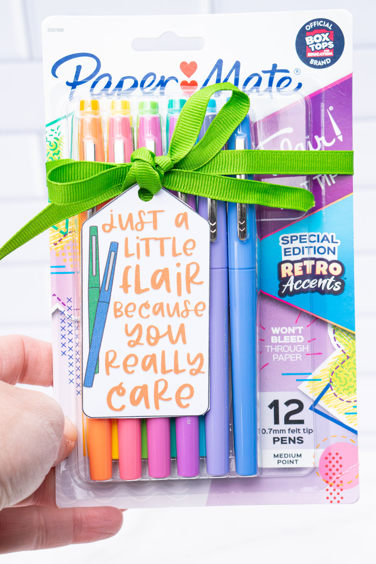 This image is of a pack of Flair pens with a green ribbon and gift tag that says just a little flair because you really care.