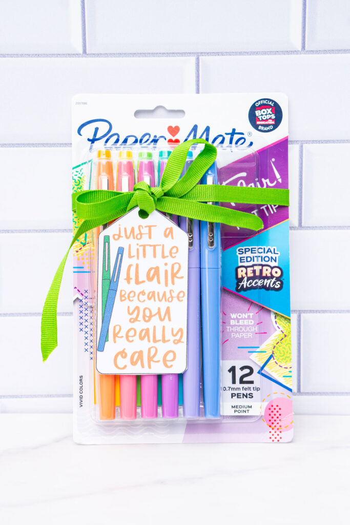 This image is of a pack of Flair pens with a green ribbon and gift tag that says just a little flair because you really care.