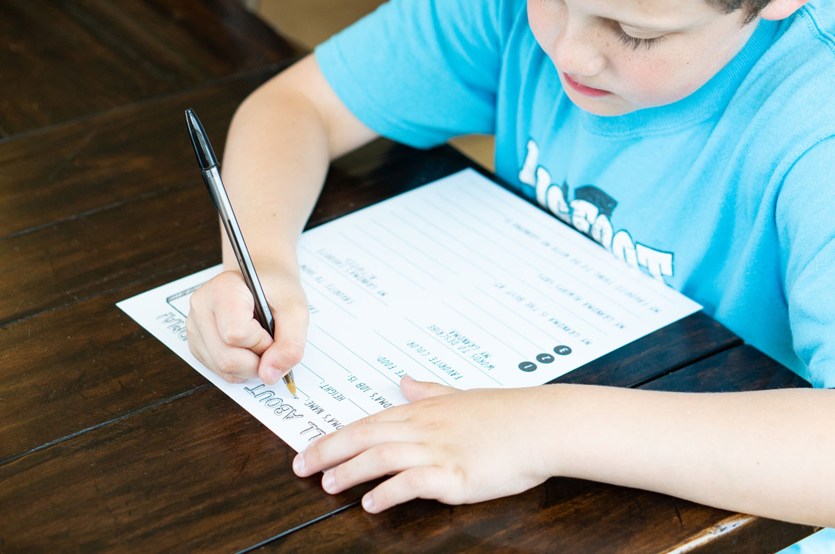 This is a picture of a boy filling in a Mother's Day all about my Mom printable that you can get for free at the end of this post.