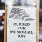 This image shows a free printable Closed for Memorial Day sign with a black and white American flag on the top left corner.