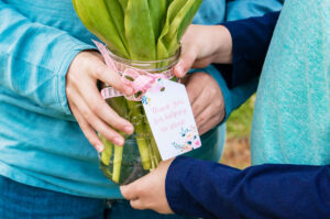 This image is of two boys holding a mason jar of flowers (purple tulips) with a gift tag that says, "Thanks for helping us grow."