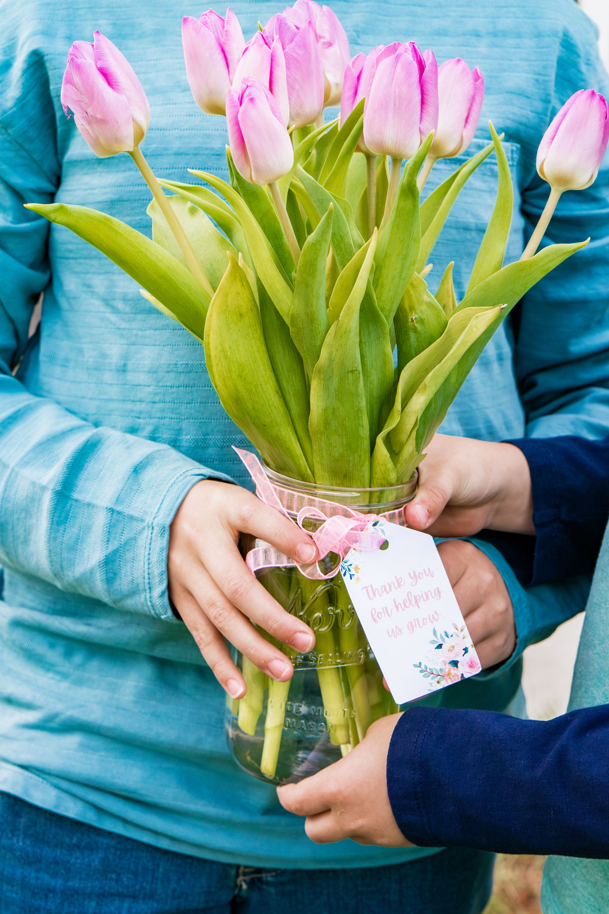 This image is of two boys holding a mason jar of flowers (purple tulips) with a gift tag that says, "Thanks for helping us grow."