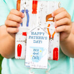This image shows a boy holding a gift bag with a wrapped present that says Happy Fathers Day with a mug which says best dad ever that you can get from the free Happy Fathers Day tags printable set at the end of this post.