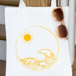 In this image, it shows one of the SVGs from the free summer SVG set. This one says salt water heals everything with the picture of waves and the sun on a tote bag.