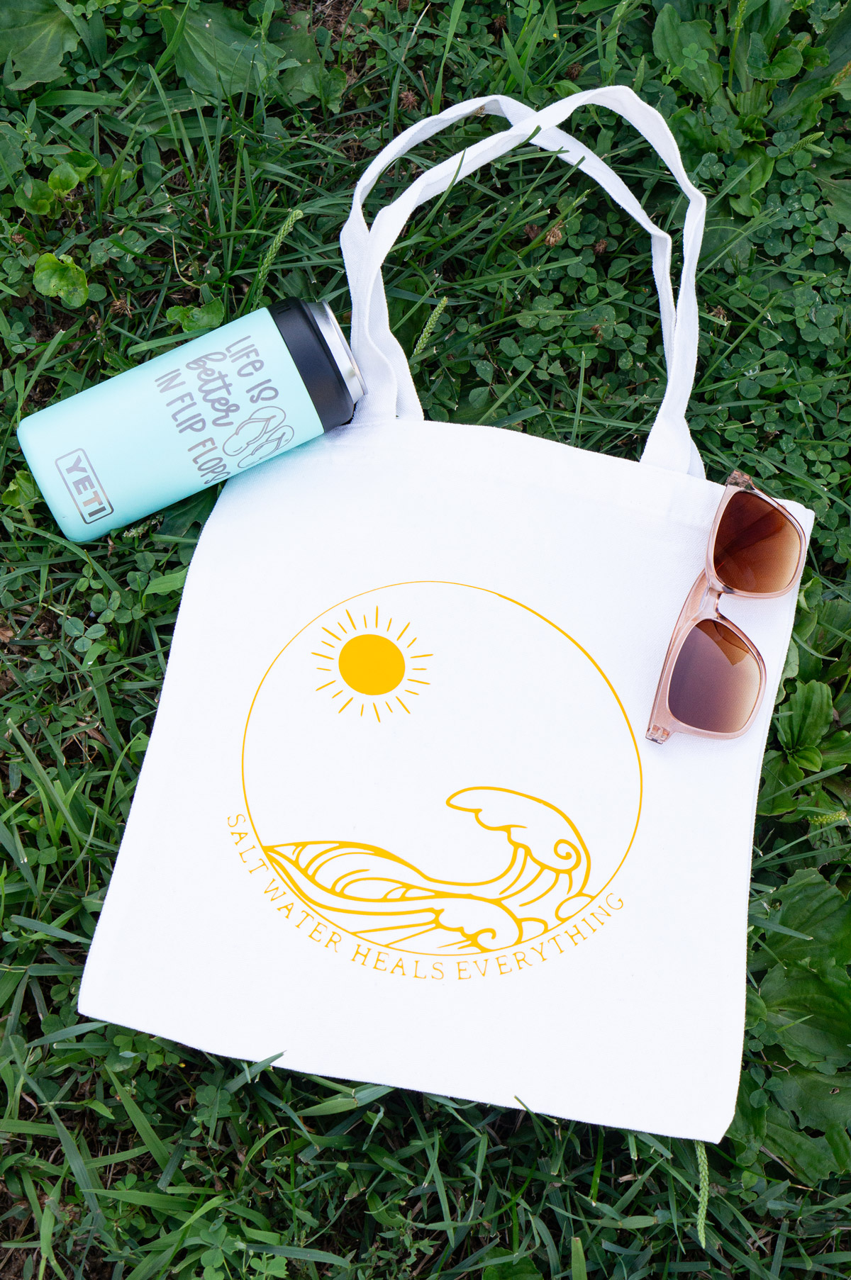 In this image, it shows two of the SVGs from the free summer SVG set. The first one says salt water heals everything with the picture of waves and the sun on a tote bag. The second one says life is better in flip flops with an image of some flip flops, engraved on a Yeti tumbler colster.