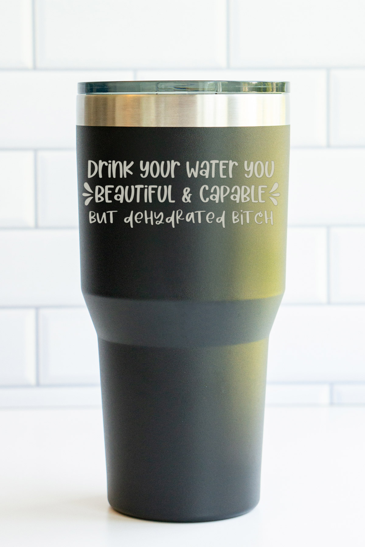 The image is of a laser engraved tumbler that says drink your water you beautiful & capable but dehydrated bitch.