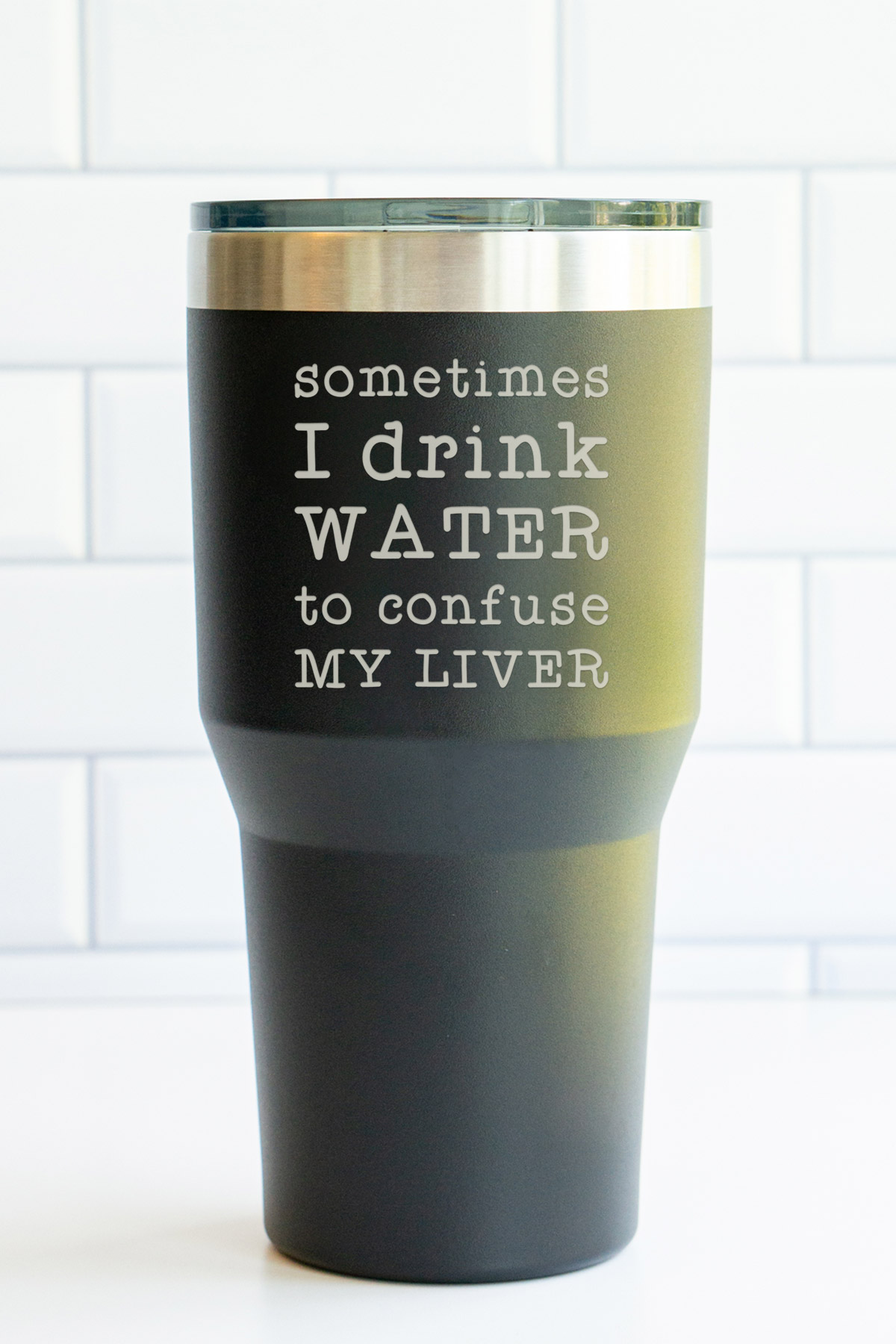 This image is of an engraved tumbler. The tumbler says sometimes I drink water to confuse my liver.