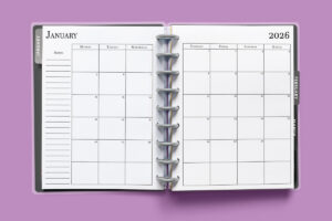 This image shows the 2026 free printable calendar you can download for free in this blog post. It is inside of an open planner on the month of January.