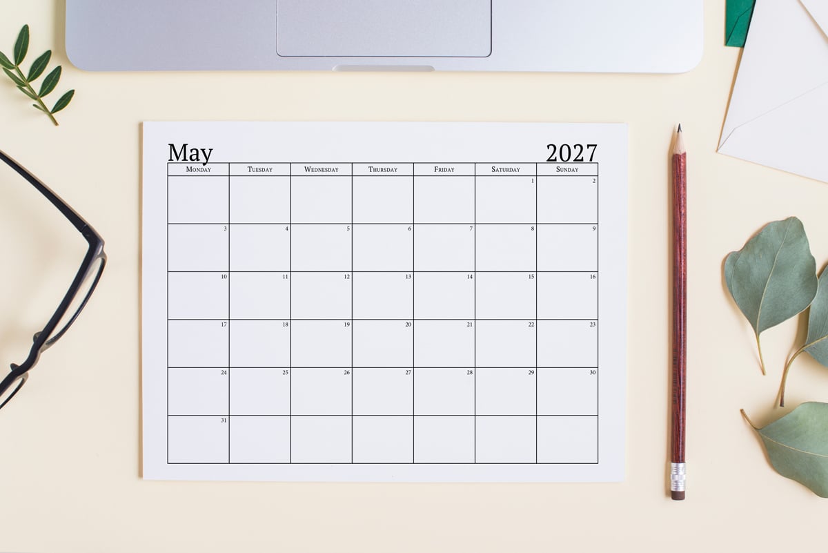 This image shows an example of the free 2027 calendar one page design you can get for free in this blog post. It's showing the month of May laying on a desk top.