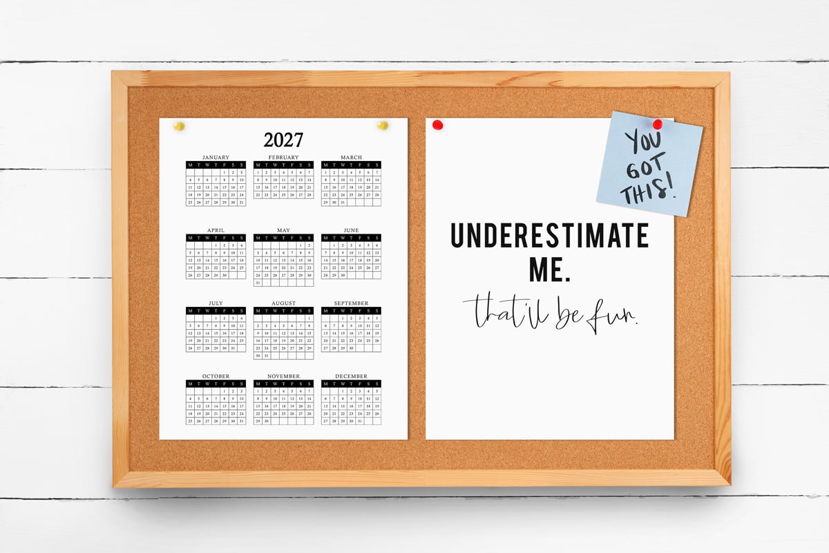 This image shows a 2027 free printable year at a glance calendar you can get for free in this blog post. The calendar is hanging on a bulletin board next to a print that says underestimate me, that'll be fun and a post it note that says you got this!