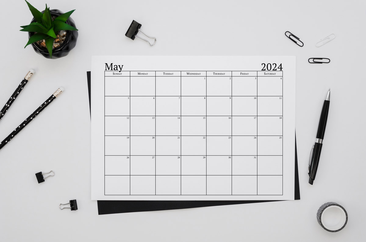 This image shows an example of the free 2024 calendar one page design you can get for free in this blog post. It's showing the month of May laying on a desk top.