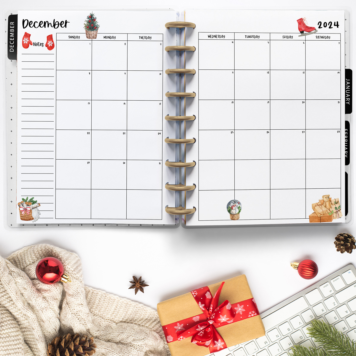 This image is an example of one of the printable 2024 calendar you can get for free at the end of this post. This is showing the month of December inside of an open planner with a keyboard, present, and blanket below.