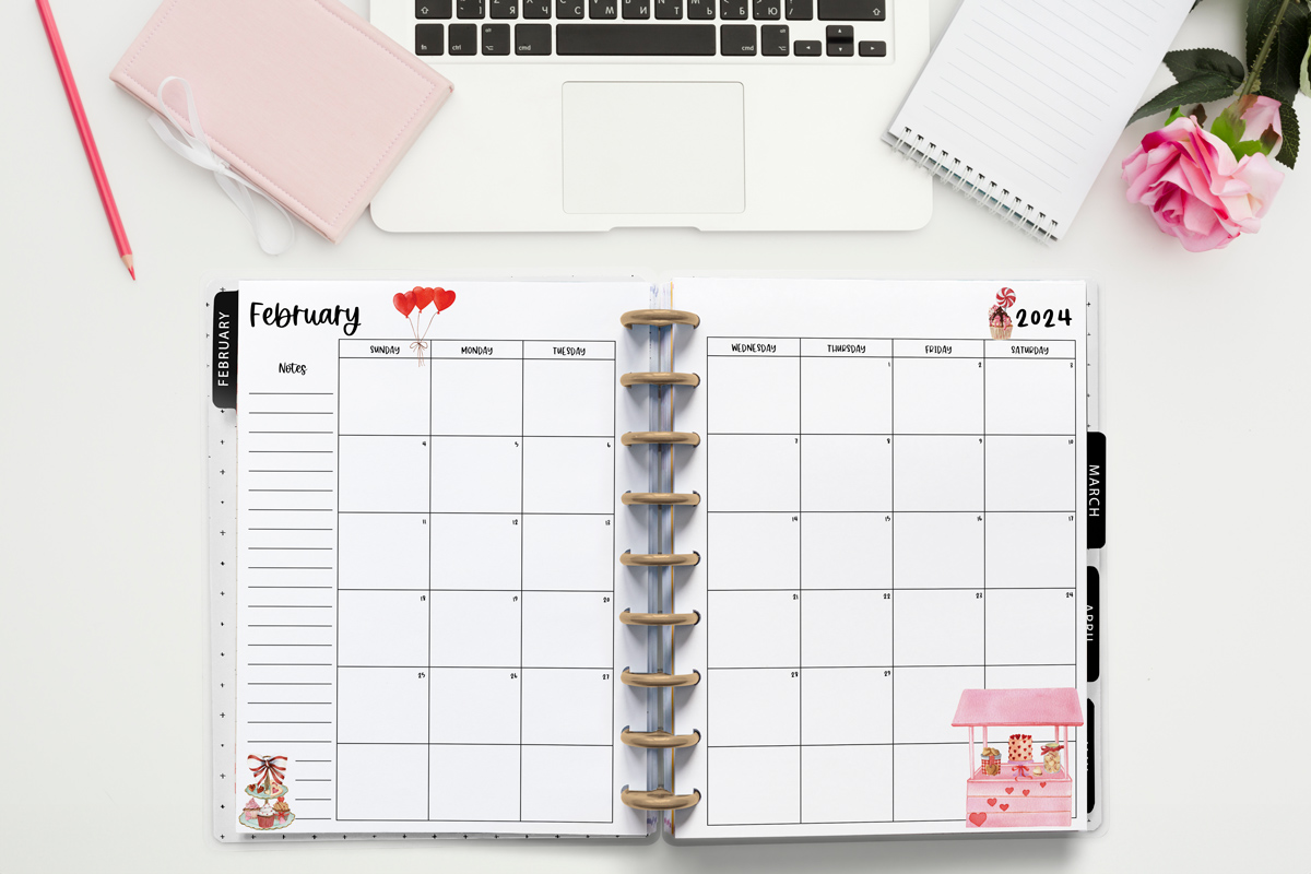 This image is an example of one of the printable 2024 calendar you can get for free at the end of this post. This is showing the month of February inside of an open planner. Above the planner is an open laptop keyboard, some paper, a pencil, headphones, and a flower.