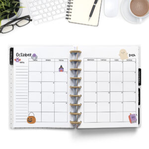 This image is an example of one of the printable 2026 calendar you can get for free at the end of this post. This is showing the month of October inside of an open planner. Above the planner is an open laptop keyboard, a notebook, a pencil, cup of coffee, a plant, and a pair of glasses.