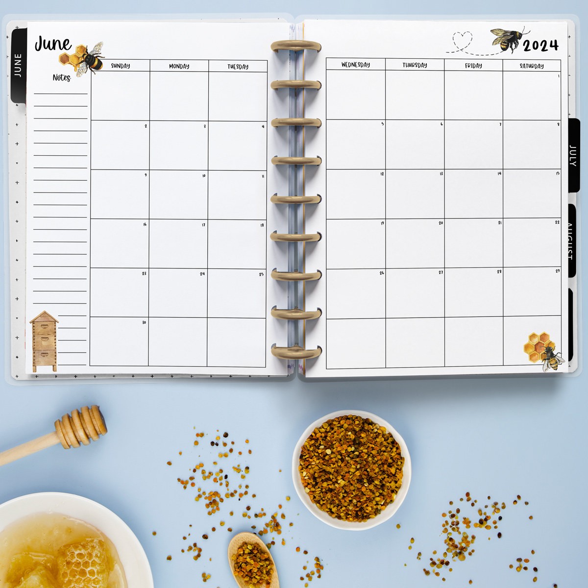 This image is an example of one of the printable 2024 calendar you can get for free at the end of this post. This is showing the month of June inside of an open planner. Below the planner is some honey, seeds, and honey comb.