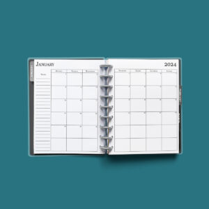 This image shows the 2024 free printable calendar you can download for free in this blog post. It is inside of an open planner on the month of January.
