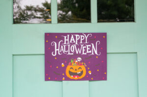 This image shows one of the free printable Halloween candy signs you can get in this free set. This sign is hanging on a door and says Happy Halloween!