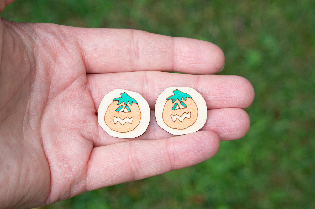 This image shows one of the pairs of earrings you can make using the Halloween earring SVG set. It's a pair of pumpkin cookie earrings inspired by Pillsbury pumpkin cookies.