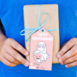 This image shows one of the free Happy Halloween printable tags tied onto a wrapped gift.
