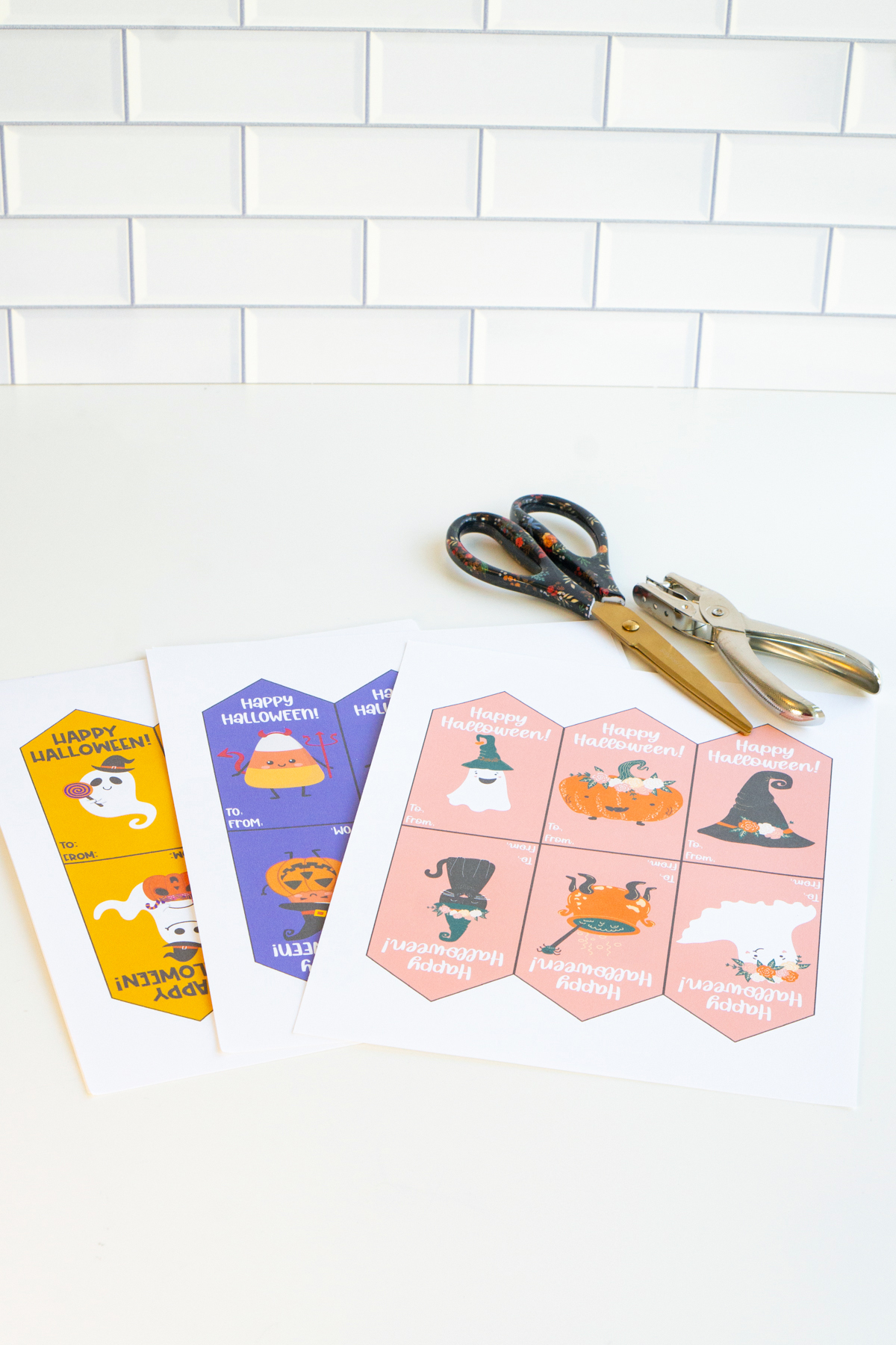This image shows the free Happy Halloween printable tags before being cut with some scissors and a hole punch.