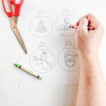 This image shows someone coloring some of the free printable Christmas ornaments you can get for free at the end of this post.