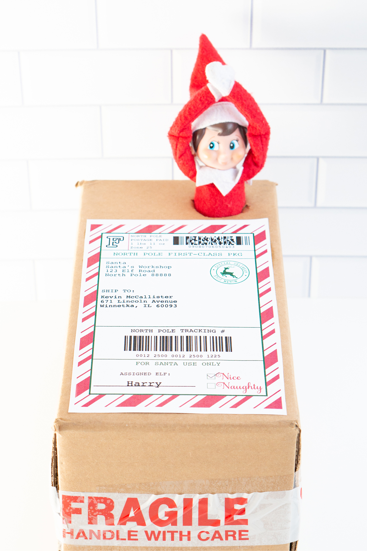 This image shows an example of the free Elf on the shelf mailing label you can download for free in this blog post on a shipping box with an Elf on the Shelf doll escaping out of the top of the box.