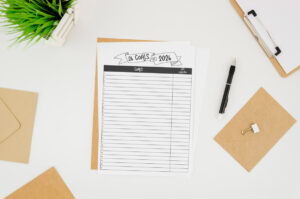 26 Goals for 2026&rsquo; printable sheet sitting on a white desk with envelopes, clipboard, pen, and a small plant.