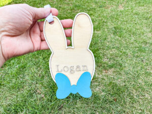 This image shows one of the Easter basket tags made out of wood using an xTool laser machine. It's in the shape of a bunny head with the name Logan on it.