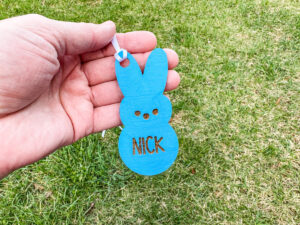 This image shows one of the Easter basket tags made out of wood using an xTool laser machine. It's in the shape of a blue bunny chick with the name Nick on it.