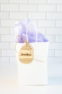 This is a picture of a laser engraved Easter egg basket tag being used a gift tag on a gift bag.