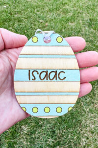 This image shows one of the Easter basket tags made out of wood using an xTool laser machine. It's in the shape of an egg and says Isaac.