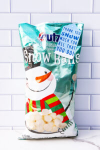 This is one of the free Christmas treat gift tags you can download in this post. It says, Thank You Snow Much for All That You Do. It features hand-drawn falling snow, a pile of snow at the bottom, and the word snow is designed to look like snow has fallen on top of it. The tag is attached to a bag of snowball cheeseballs.