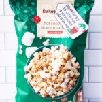 This is one of the free Christmas treat gift tags you can download in this post. It says, Poppin’ By to Wish You a Very Merry Christmas. It has a hand-drawn Grinch hand reaching out stealing popcorn from a red cup of popcorn. The tag is attached to a bag of hot chocolate and marshmallow flavored popcorn.
