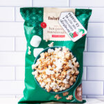 This is one of the free Christmas treat gift tags you can download in this post. It says, Poppin’ By to Wish You a Very Merry Christmas. It has a hand-drawn Grinch hand reaching out stealing popcorn from a red cup of popcorn. The tag is attached to a bag of hot chocolate and marshmallow flavored popcorn.