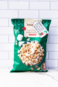 This is one of the free Christmas treat gift tags you can download in this post. It says, Poppin’ By to Wish You a Very Merry Christmas. It has a hand-drawn Grinch hand reaching out stealing popcorn from a red cup of popcorn. The tag is attached to a bag of hot chocolate and marshmallow flavored popcorn.