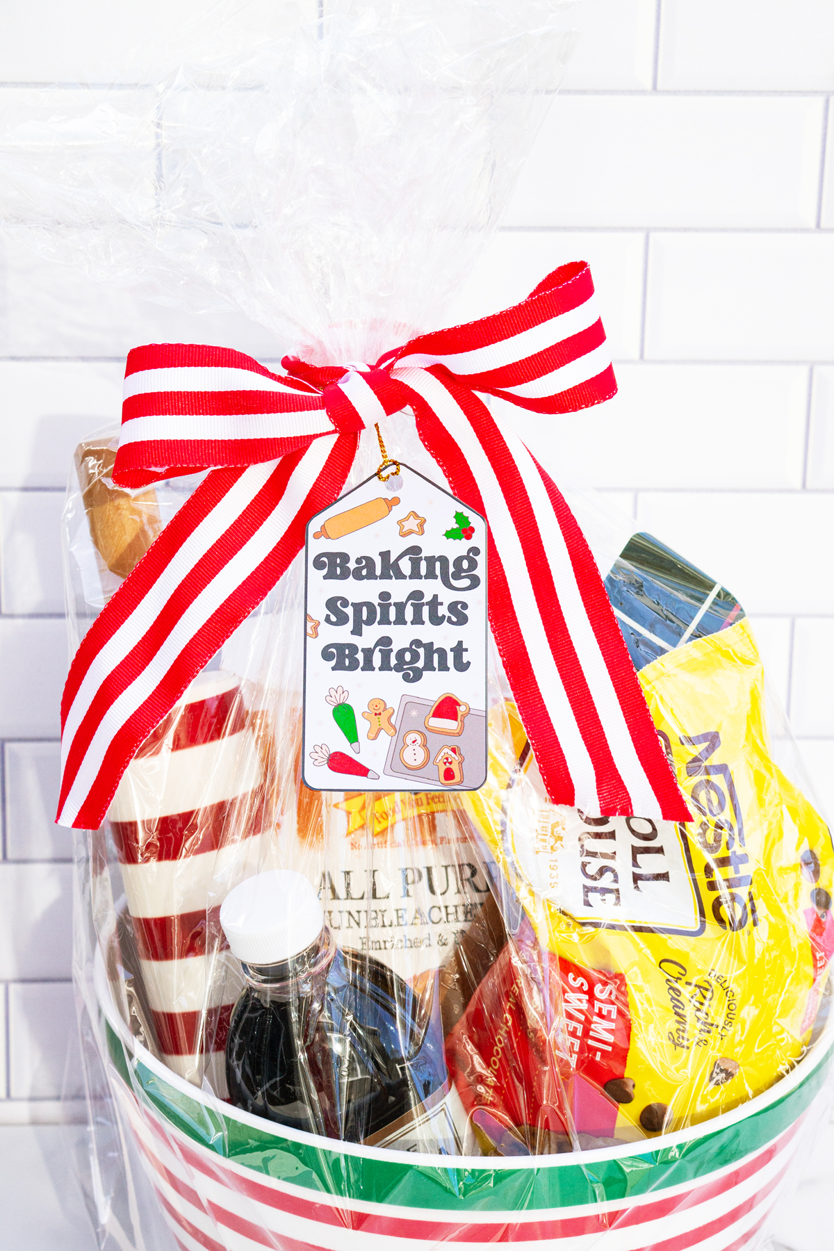 This is one of the free Christmas treat gift tags you can download in this post. It says, Baking Spirits Bright featuring Christmas cookies and baking supplies. It is attached to a gift basket filled with Christmas baking supplies, a Christmas red and white stripped rolling pin, and a red and green spatula.